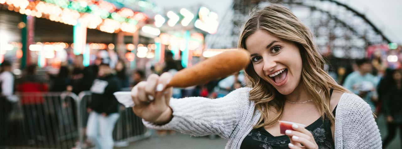 A fairgoer shows off her corndog on the midway at the state fair.